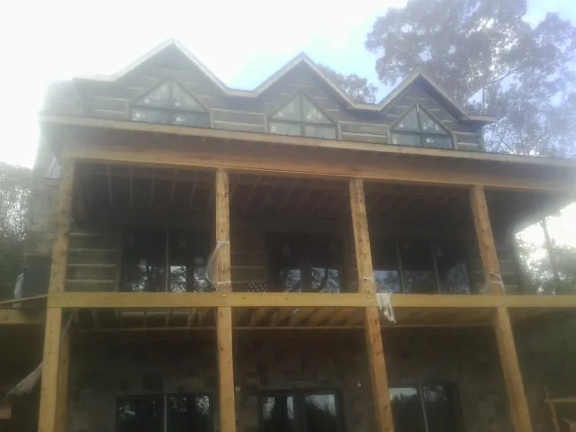 Dormers and porch framing on a large log home under construction — Roof Coating work by our crew in Burkittsville