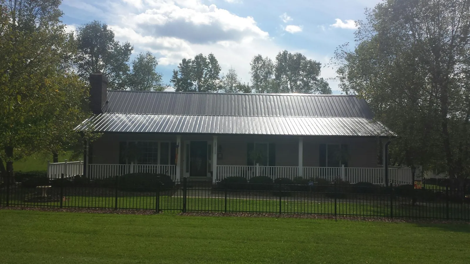 Gray metal roof on a brick ranch with a full width front porch — Gutter Guard Installation work by our crew in Burkittsville
