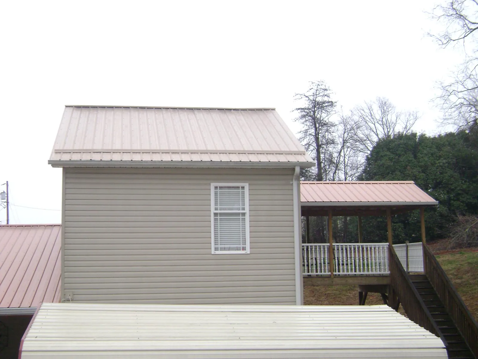 Tan metal roofs on a two story addition and attached porch, from a Roof Replacement job in Burkittsville