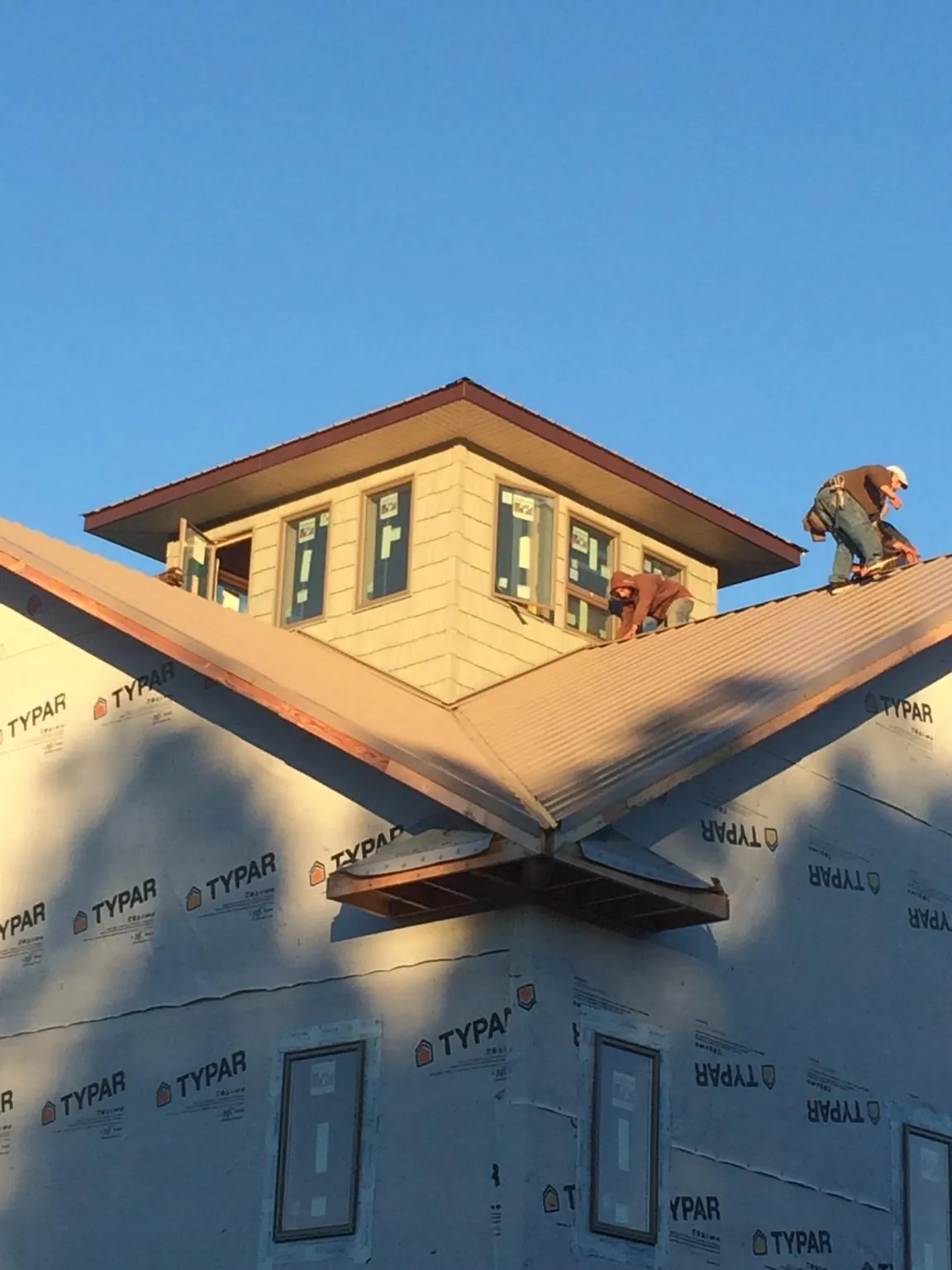 Roofers working around a rooftop cupola on a new metal roof at sunset — Roof Waterproofing in Burkittsville by Roofing Brothers